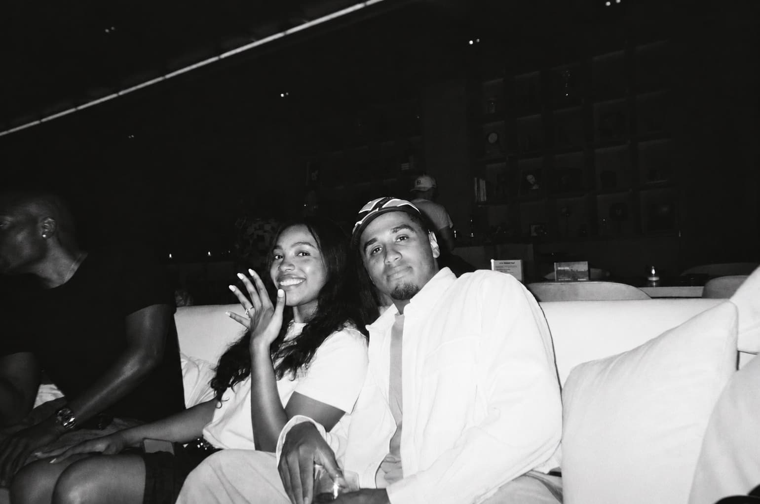 Black-and-white photograph of Cayla and Shaddy seated together, framed as a tropical postcard